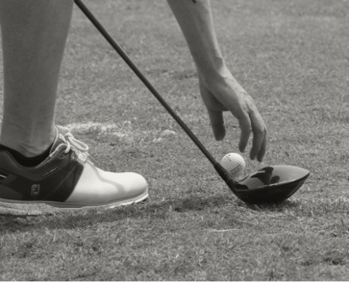 Golfer placing golf ball on tee.